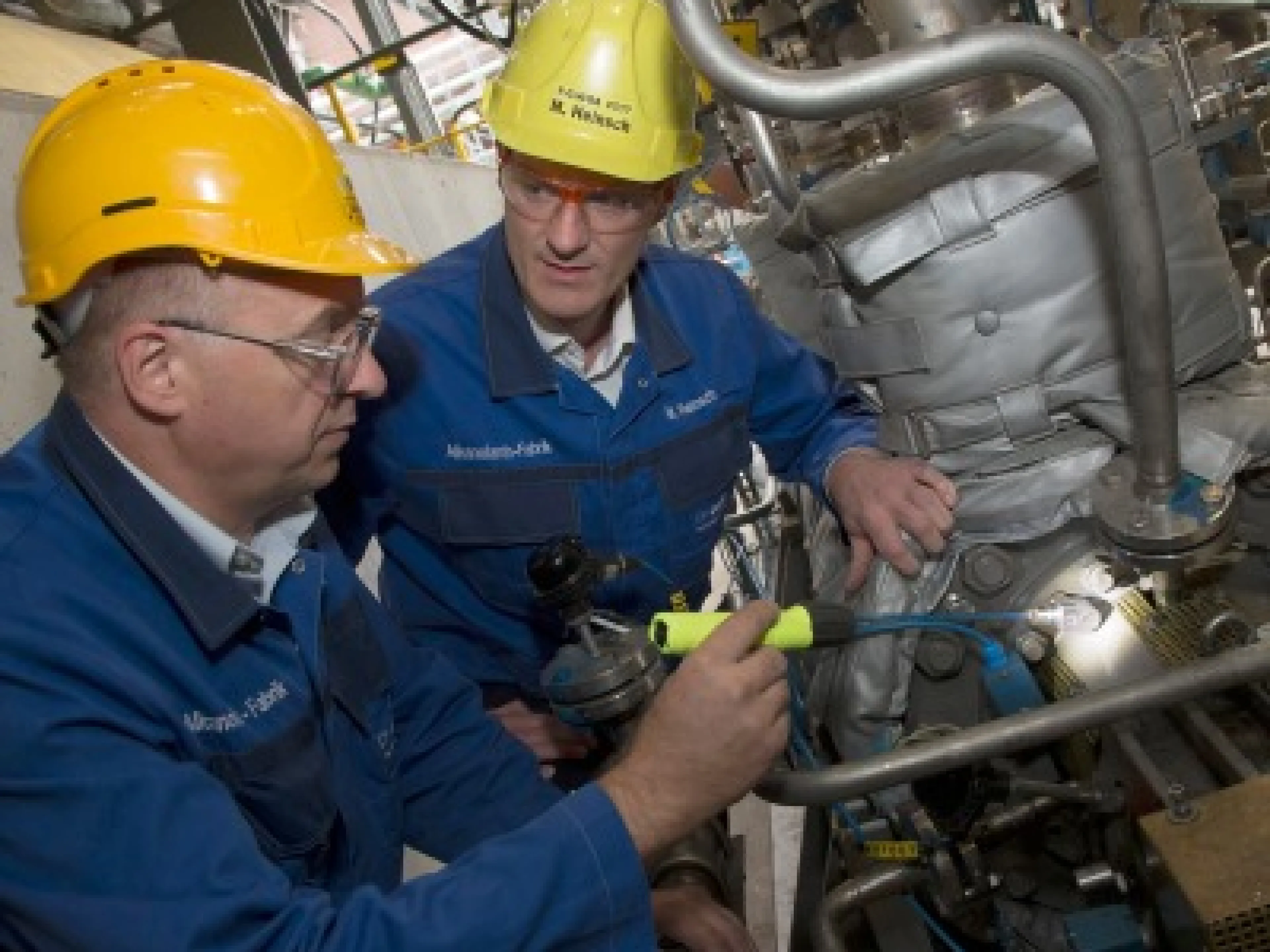 Zwei BASF-Mitarbeiter überprüfen an einer Amine-Produktionsanlage einen Sensor an einer Pumpe